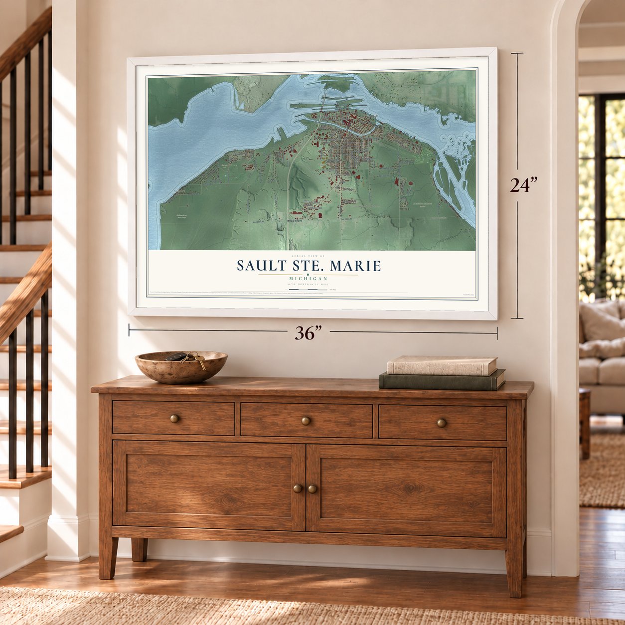 Sault Ste. Marie, Michigan map, 24 x 36 inch print in a white frame above a dresser by a staircase