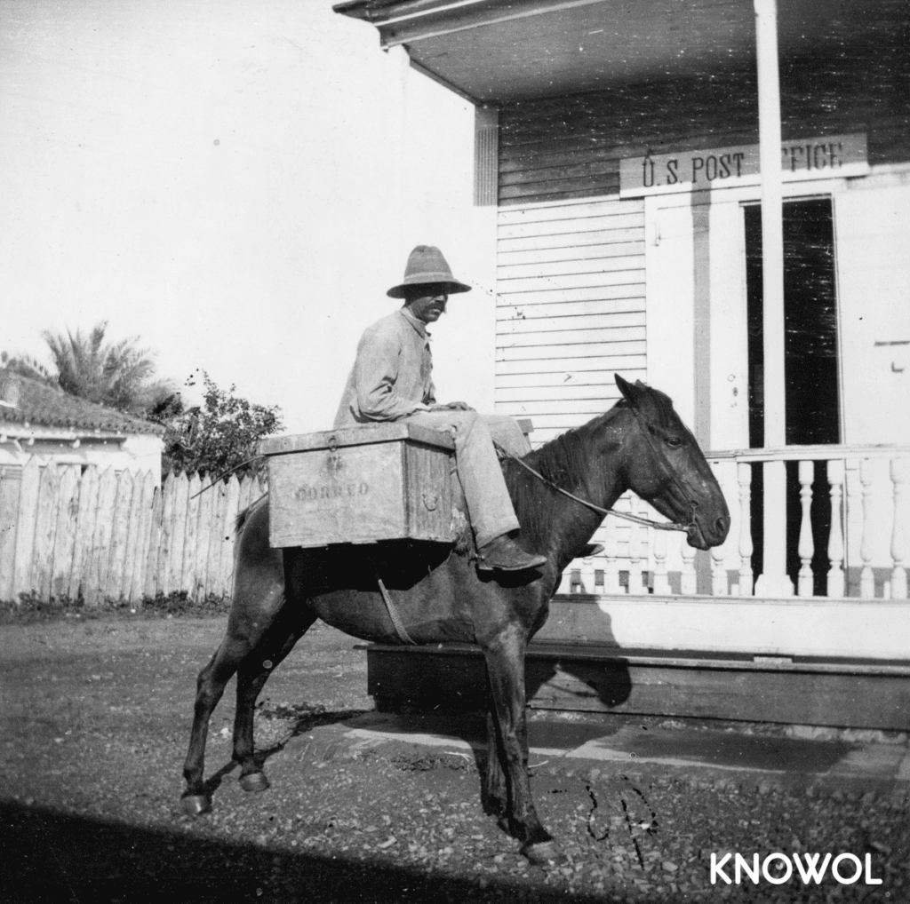 This picture shows a Puerto Rican mail carrier on a horse with a wooden box labeled "correo", meaning "mail" in English.