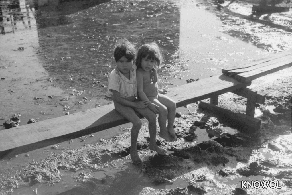 Children sitting on one of the boardwalks which act as sidewalks in the slum area known as "El Fangitto" (The Mud) in San