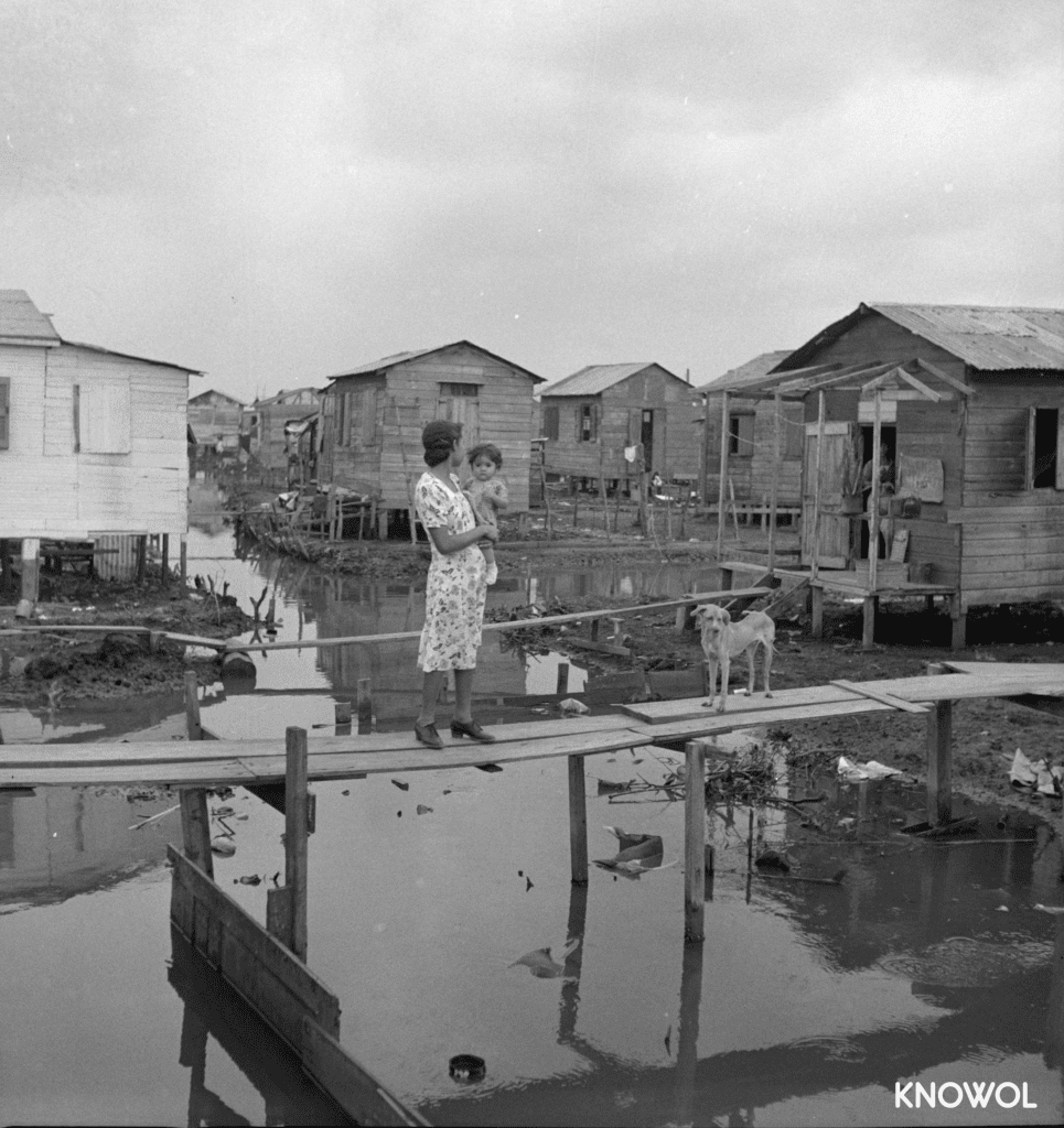 A woman stands with her child and dog on one of the boardwalks used to get to her home in "El Fangitto".