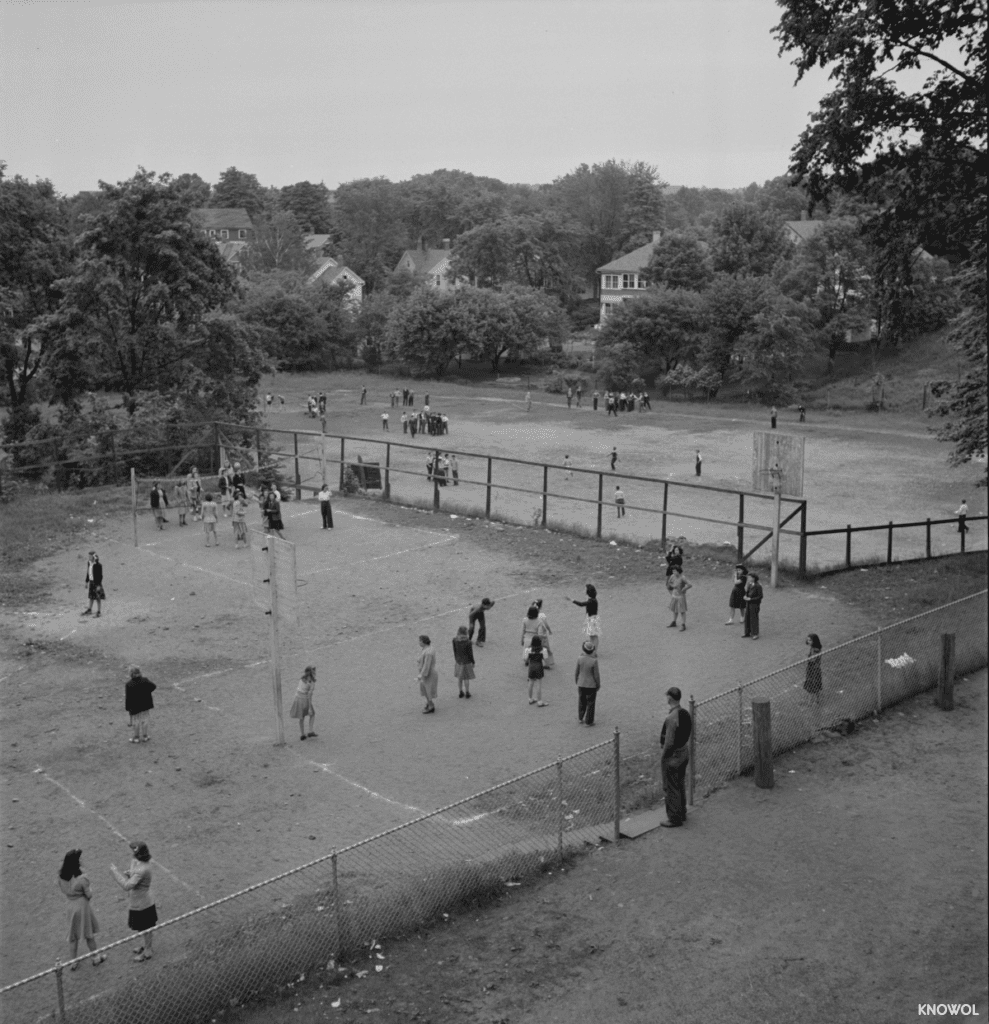 A dirt playground featuring basketball hoops and a volleyball net.