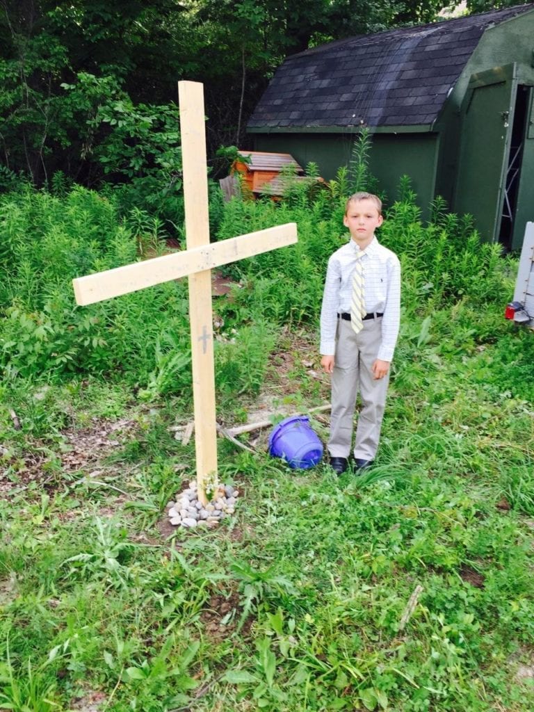 This little boy's turtle died, so he dug a grave, built a cross, and put on a shirt and tie for the funeral.