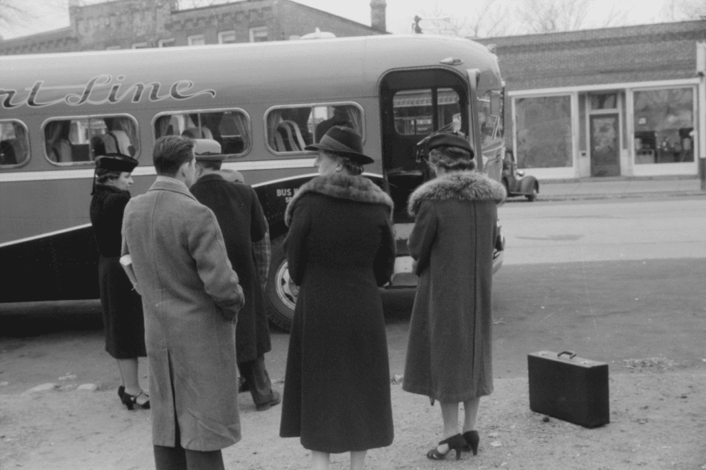 A well dressed group waits to board the bus.