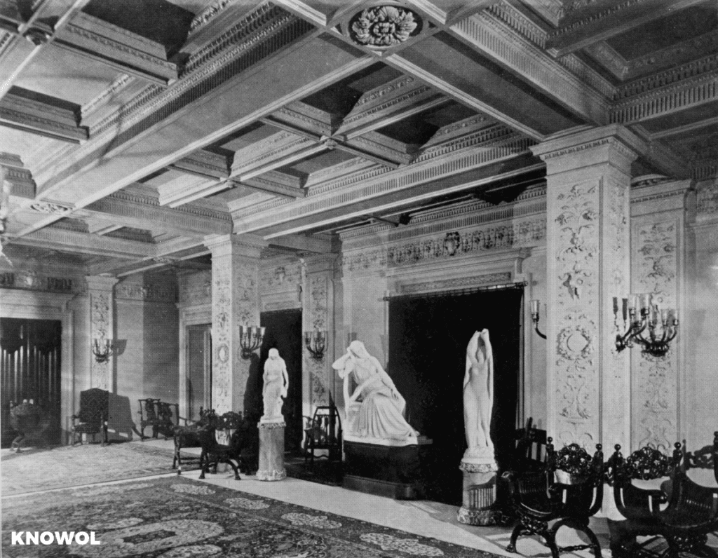 Foyer in the Waldorf Astoria, New York City, showing three statues, decorative ceiling, and chairs.