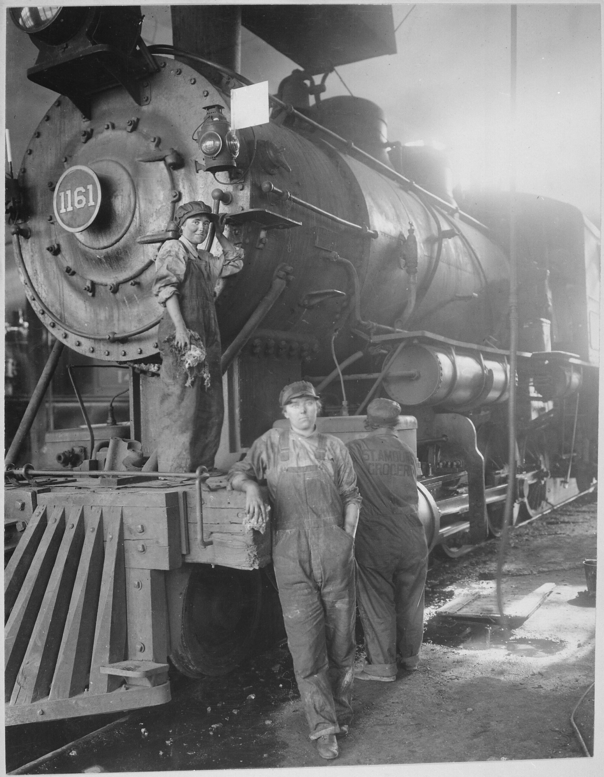 Three women in overalls and caps with cleaning rags at Great Northern locomotive 1161, Great Falls, Montana, about 1918